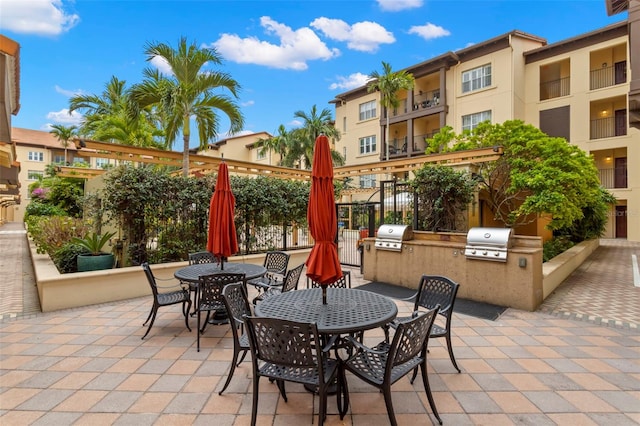 view of patio with outdoor dining space, area for grilling, a grill, and fence