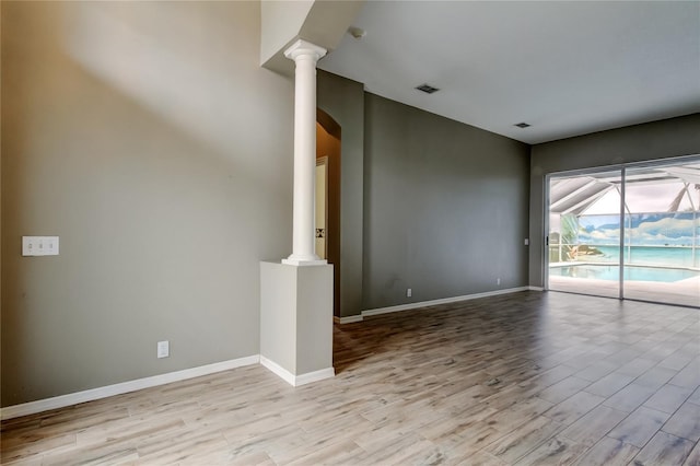 spare room featuring visible vents, baseboards, wood finished floors, and ornate columns