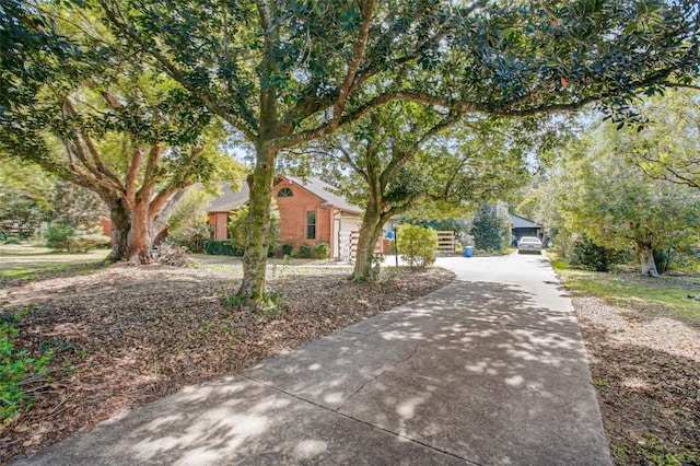 view of side of property with a garage, brick siding, and driveway