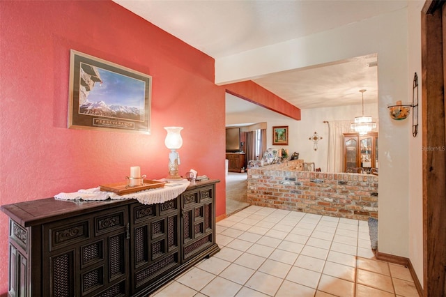 hallway featuring beamed ceiling, baseboards, and light tile patterned floors