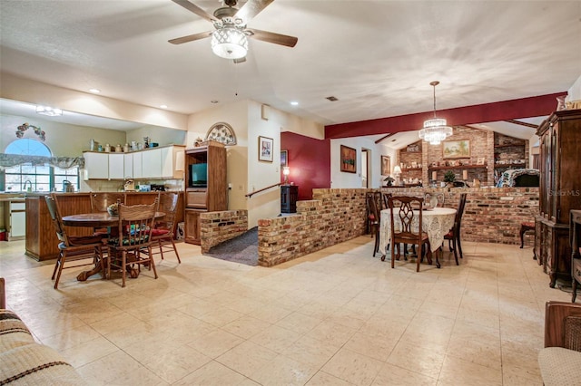 dining space with visible vents, brick wall, vaulted ceiling, light floors, and ceiling fan with notable chandelier