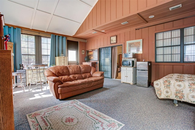 living room featuring lofted ceiling, wood walls, carpet flooring, and visible vents