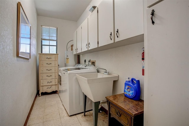 washroom with washing machine and dryer, a sink, baseboards, water heater, and cabinet space