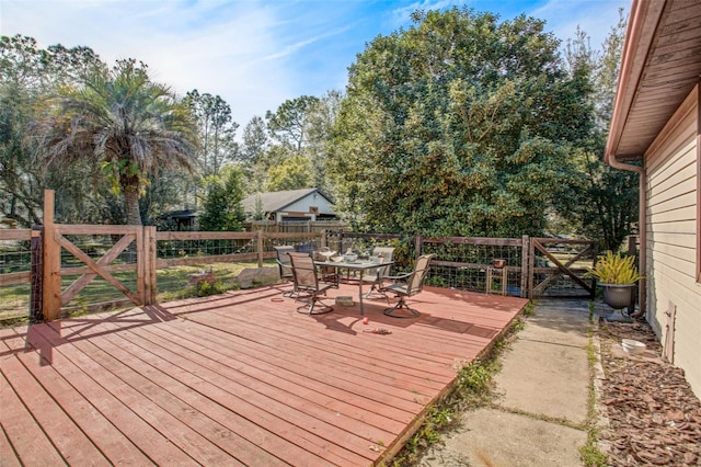 deck with outdoor dining space, fence, and a gate