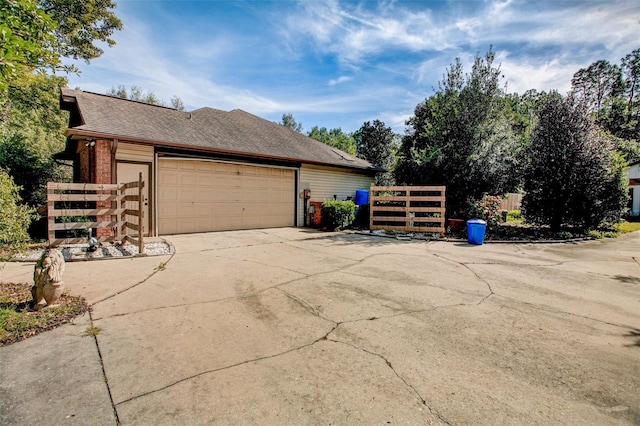 view of side of property featuring an attached garage, fence, concrete driveway, and brick siding