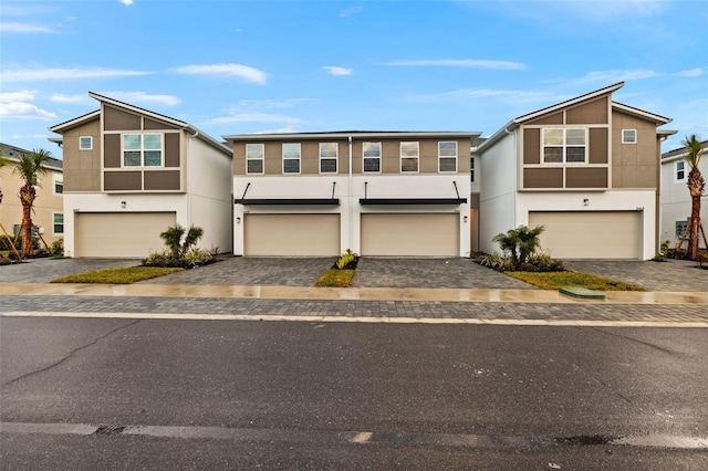 view of front of property with stucco siding, a garage, and decorative driveway