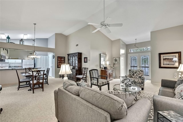 living area with high vaulted ceiling, a ceiling fan, french doors, and light colored carpet