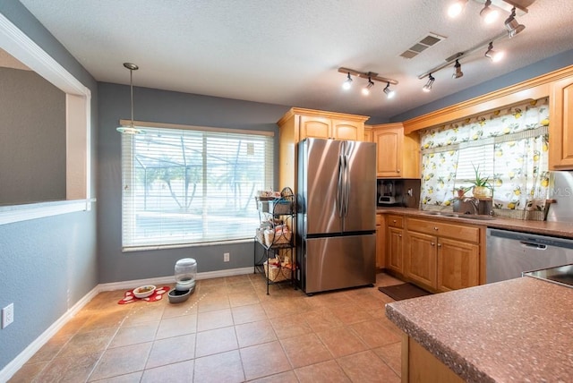 kitchen with dark countertops, stainless steel appliances, visible vents, a sink, and decorative light fixtures