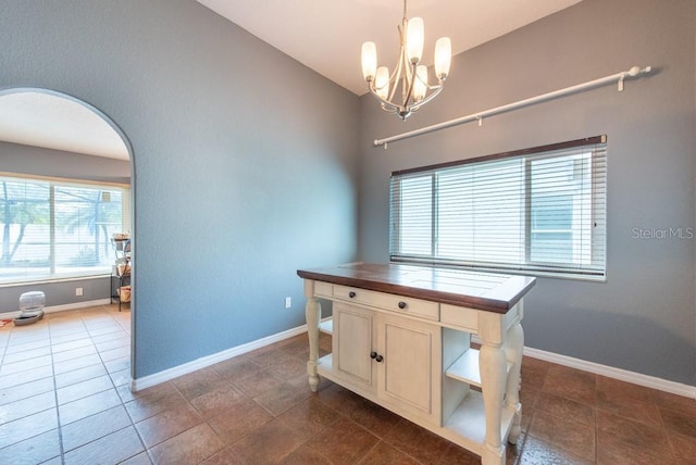 dining room with arched walkways, vaulted ceiling, baseboards, and a notable chandelier