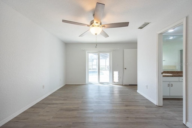 spare room featuring visible vents, baseboards, a textured ceiling, light wood-type flooring, and ceiling fan