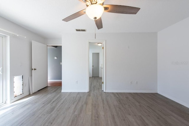 unfurnished bedroom with baseboards, ceiling fan, visible vents, and wood finished floors