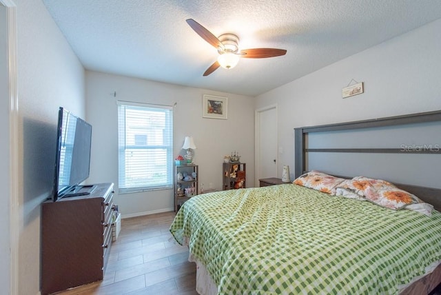 bedroom with a textured ceiling, a ceiling fan, and baseboards