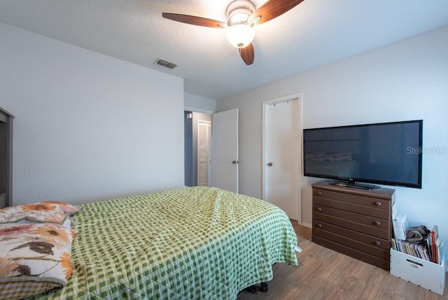 bedroom with visible vents, a ceiling fan, a textured ceiling, and wood finished floors