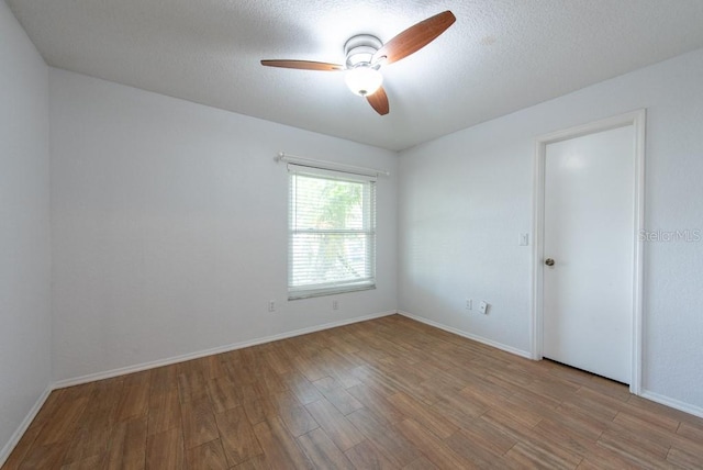 unfurnished room with baseboards, ceiling fan, light wood-style floors, and a textured ceiling