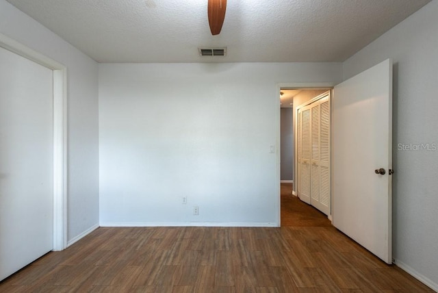 empty room featuring baseboards, visible vents, a ceiling fan, dark wood-type flooring, and a textured ceiling