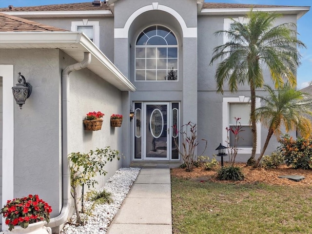 property entrance featuring a lawn and stucco siding