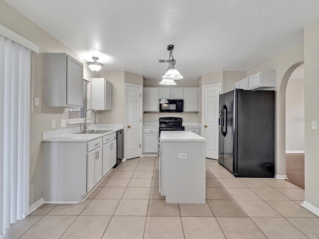 kitchen with black appliances, a sink, arched walkways, a kitchen island, and light countertops