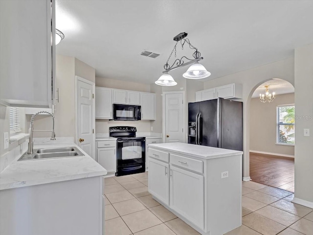 kitchen with black appliances, a sink, arched walkways, light tile patterned floors, and white cabinetry