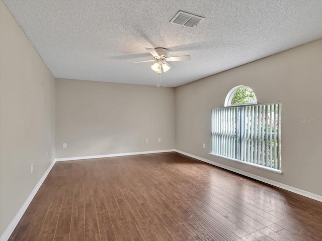 empty room with a ceiling fan, dark wood finished floors, a textured ceiling, and baseboards