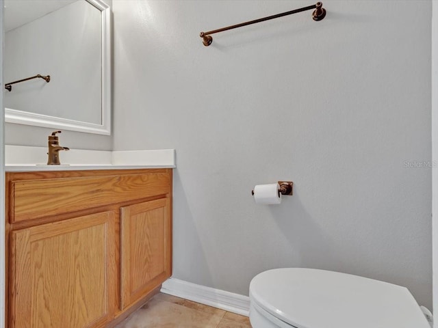 half bath with toilet, vanity, baseboards, and tile patterned floors