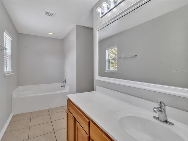 full bath with tile patterned floors, a garden tub, vanity, and baseboards