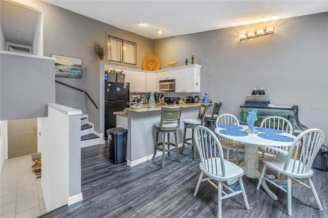 dining space featuring dark wood-style floors, baseboards, and stairs