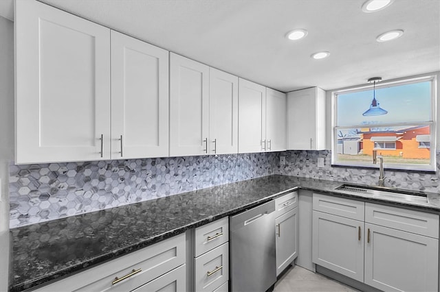 kitchen featuring a sink, dark stone counters, white cabinets, and dishwasher