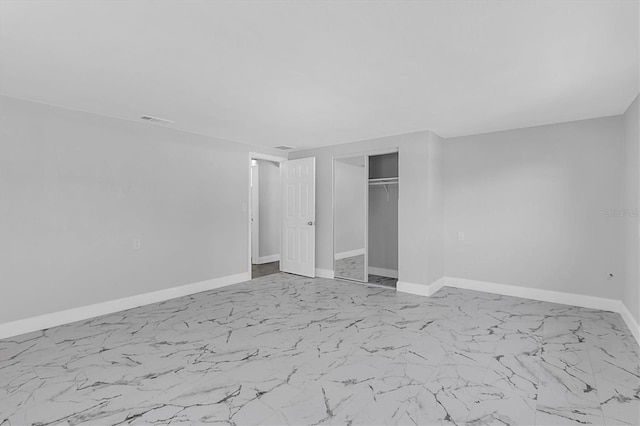 unfurnished bedroom with a closet, marble finish floor, visible vents, and baseboards