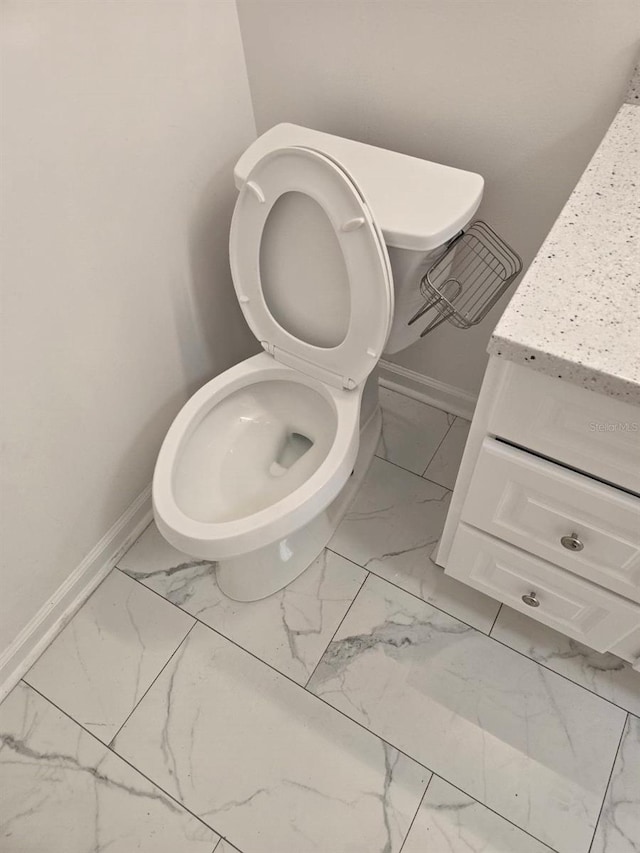 half bathroom with baseboards, toilet, and marble finish floor