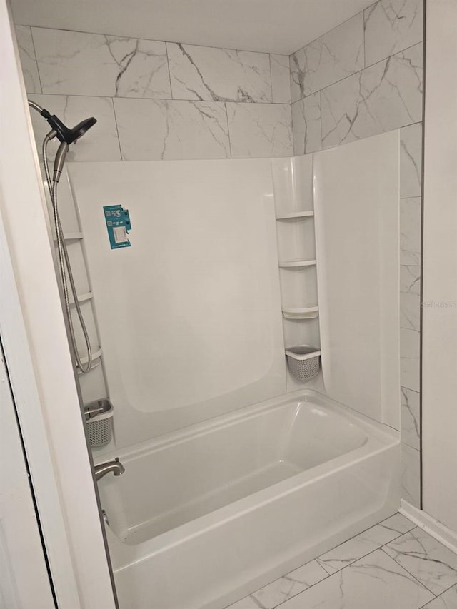 bathroom with marble finish floor and bathtub / shower combination