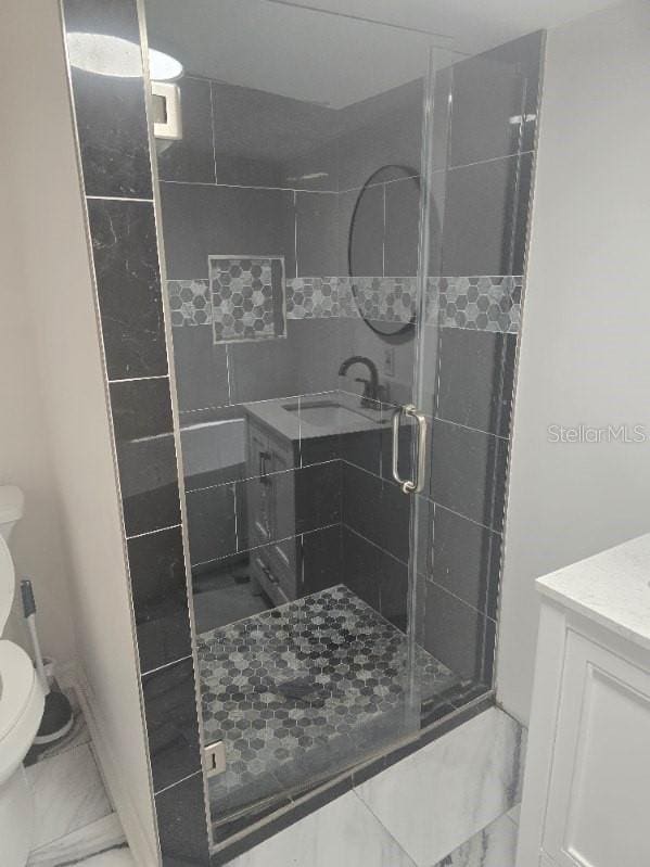 bathroom with vanity, marble finish floor, toilet, and a shower stall