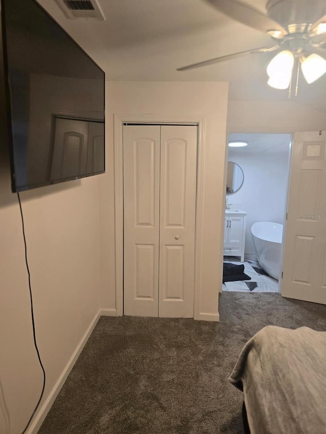 carpeted bedroom with ensuite bathroom, visible vents, a closet, and baseboards