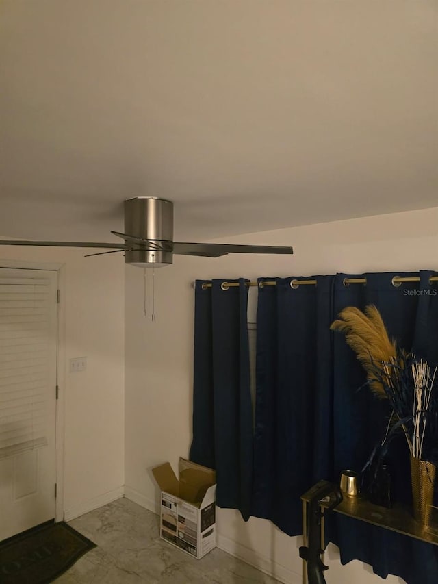 interior space featuring baseboards and ceiling fan