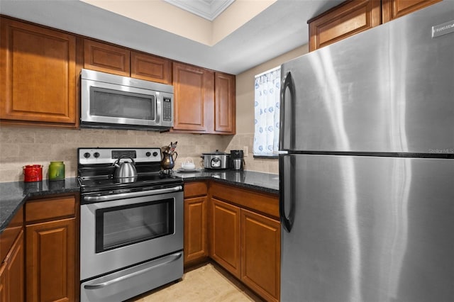 kitchen featuring appliances with stainless steel finishes, dark stone countertops, backsplash, and brown cabinets