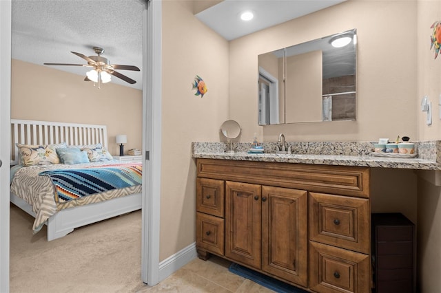 bathroom featuring connected bathroom, vanity, a textured ceiling, ceiling fan, and baseboards