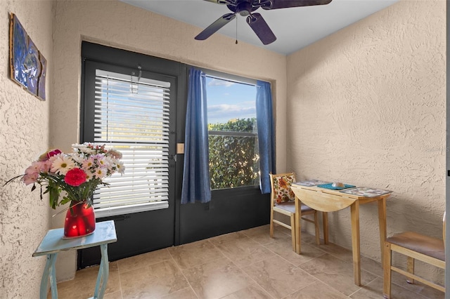 doorway with a ceiling fan and a textured wall