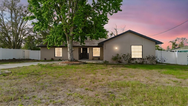 ranch-style home with stucco siding, fence, and a lawn