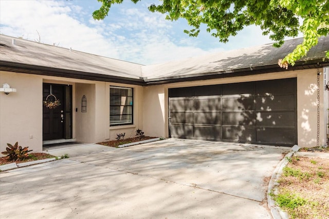 exterior space with a garage, driveway, a shingled roof, and stucco siding