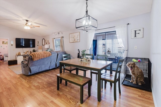 dining space featuring a wealth of natural light, vaulted ceiling, light wood finished floors, and ceiling fan with notable chandelier