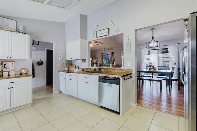 kitchen featuring light tile patterned floors, stainless steel appliances, lofted ceiling, white cabinets, and a sink