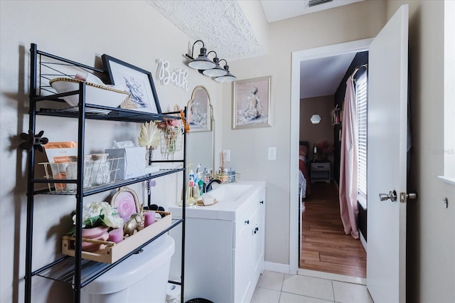 ensuite bathroom featuring visible vents, connected bathroom, toilet, tile patterned flooring, and vanity