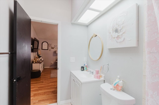 bathroom featuring toilet, wood finished floors, vanity, and baseboards