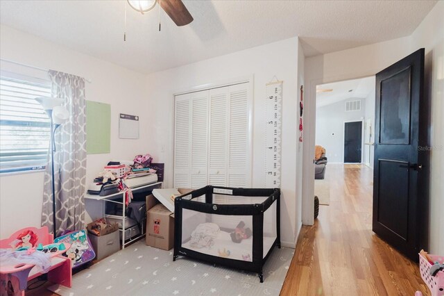 bedroom featuring ceiling fan, a textured ceiling, visible vents, light wood-style floors, and a closet