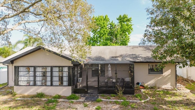 rear view of house with a sunroom and stucco siding