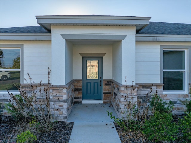 property entrance with stone siding and roof with shingles