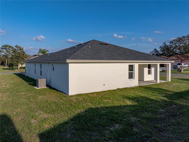 rear view of property featuring cooling unit, a yard, and stucco siding