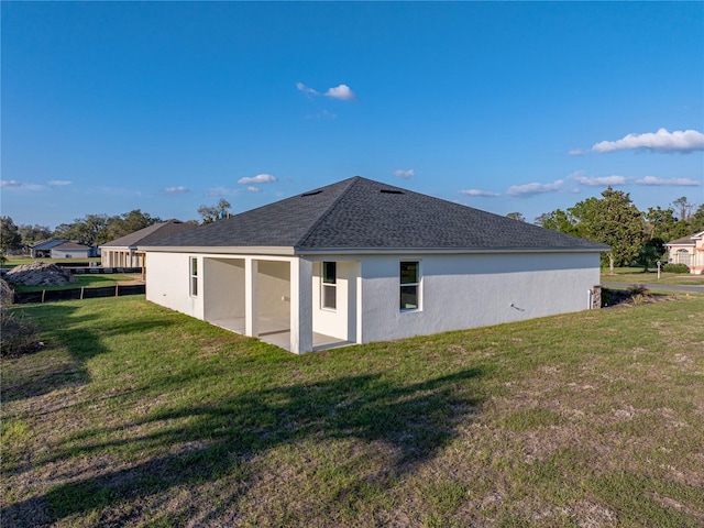 back of house with a yard, a shingled roof, a patio, and stucco siding