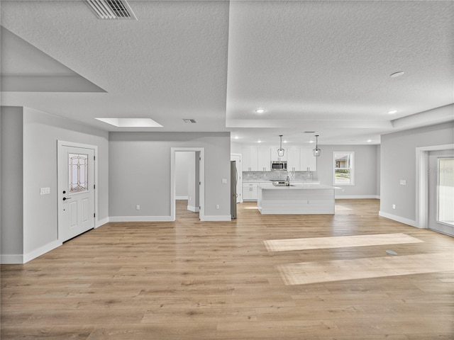 unfurnished living room featuring light wood-style floors, recessed lighting, visible vents, and baseboards