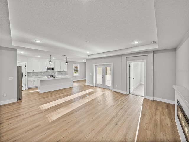 unfurnished living room with light wood-style floors, recessed lighting, french doors, and baseboards