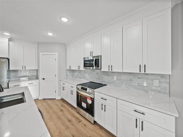 kitchen featuring appliances with stainless steel finishes, a sink, and white cabinetry